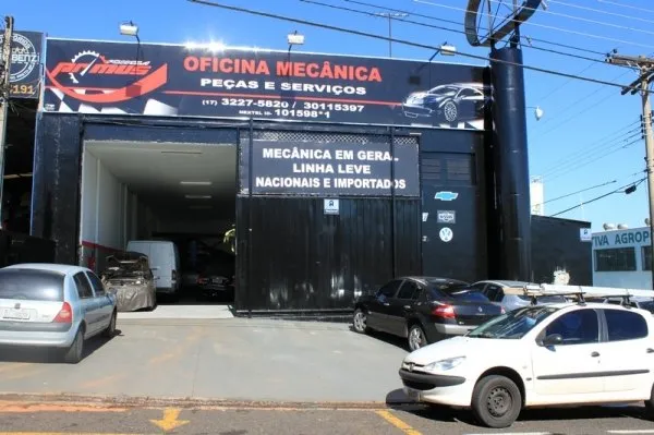Fachada da oficina vista da rua, com o letreiro Oficina Mecânica, Peças e Serviços e os telefones (17) 3227-5820 e 3011-5397