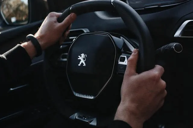 Mãos ao volante de um Peugeot, vistas do banco do motorista